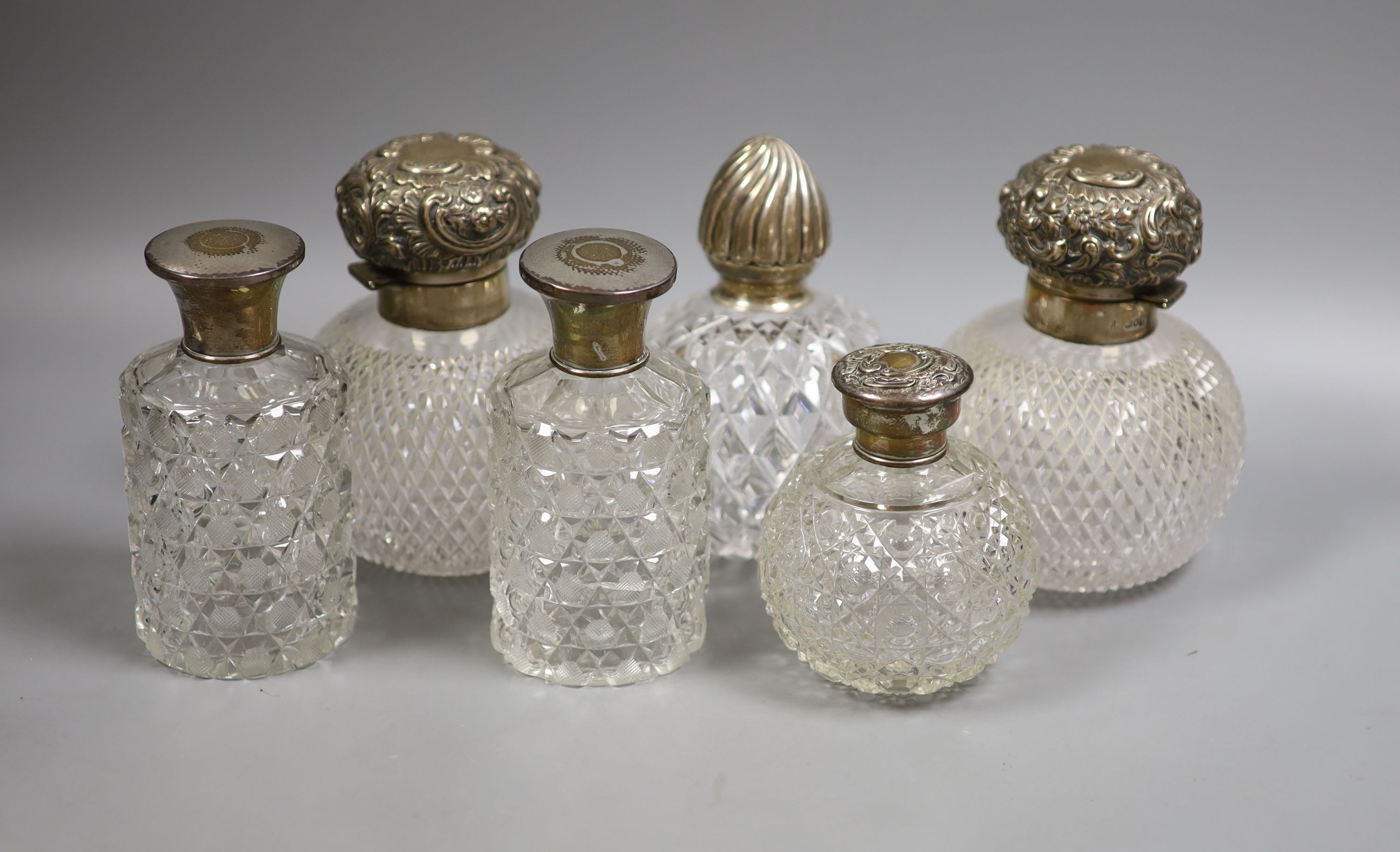 Six assorted silver topped glass scent bottles, including a pair by Chares Stuart Harris, London, 1899, height 14.4cm.